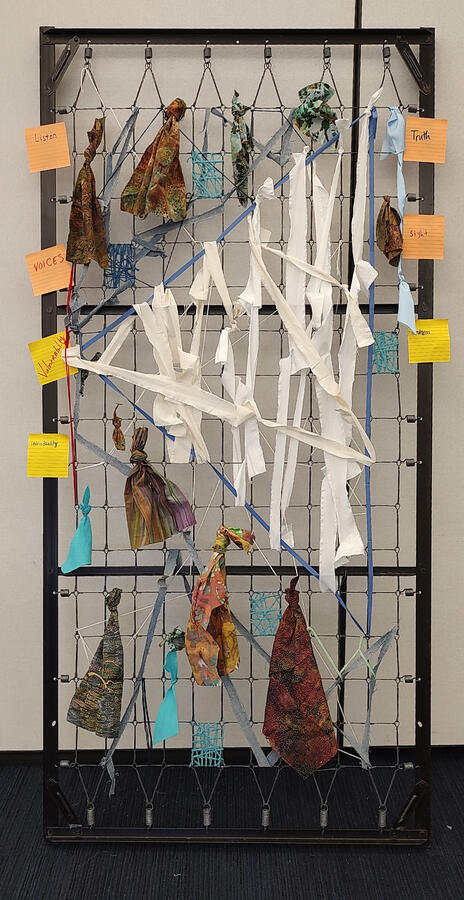 Shark tooth - a bed frame with colorful yarn wrapped around the wire except for an area with white bandages made to look like a shark tooth.