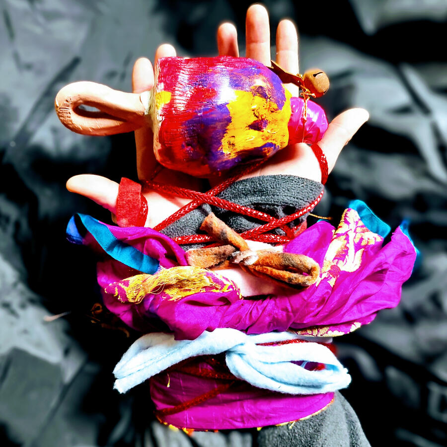 Freedom Hope - a hand bound by colorful textile, holding a colorful ceramic rattle.
